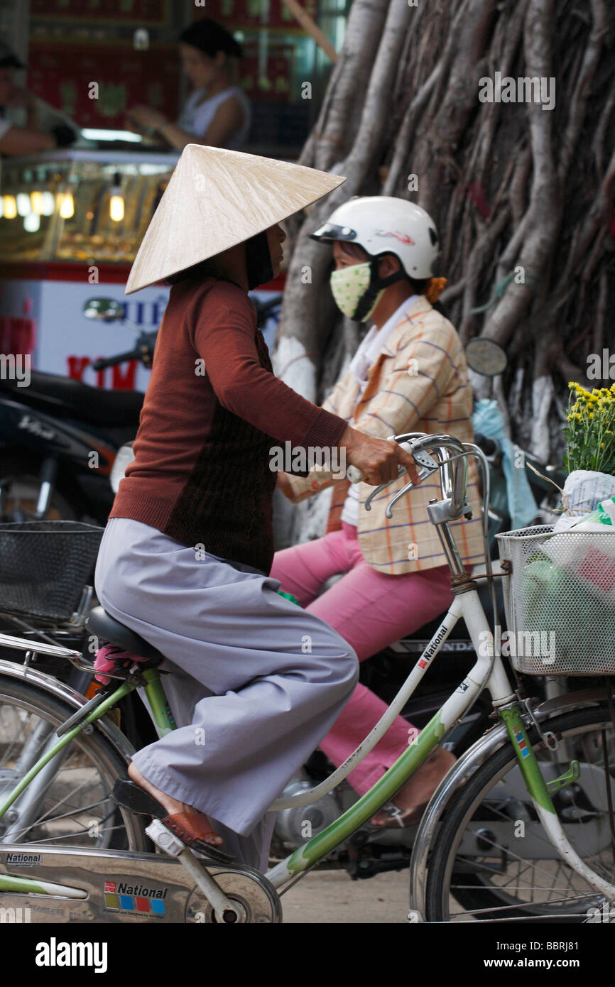 Vietnamese woman riding bike and wearing traditional conical hat, "Hoi An", Vietnam Stock Photo