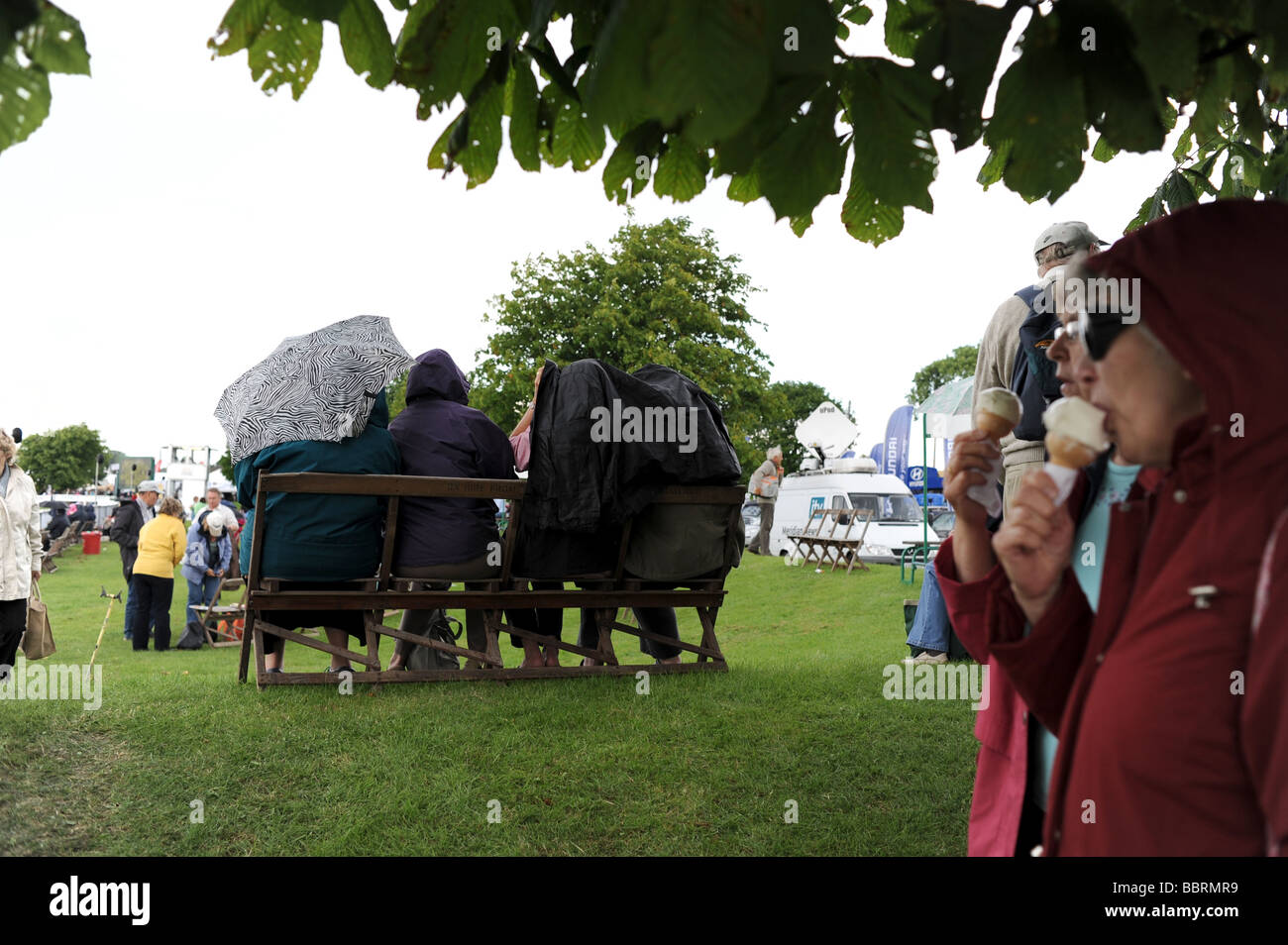Typical British summers day as people get under umbrellas and shelter from rain at the South of England Show Stock Photo