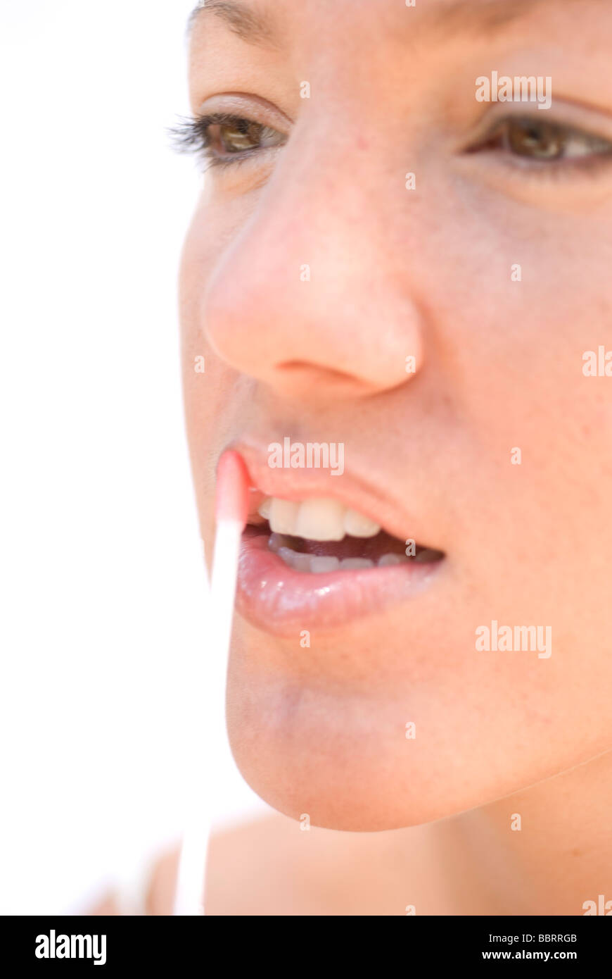 Young Woman Applying Lip Gloss Stock Photo