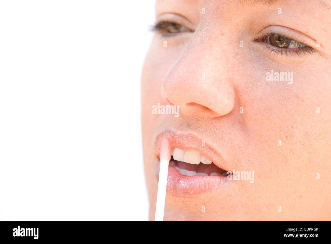 Young Woman Applying Lip Gloss Stock Photo