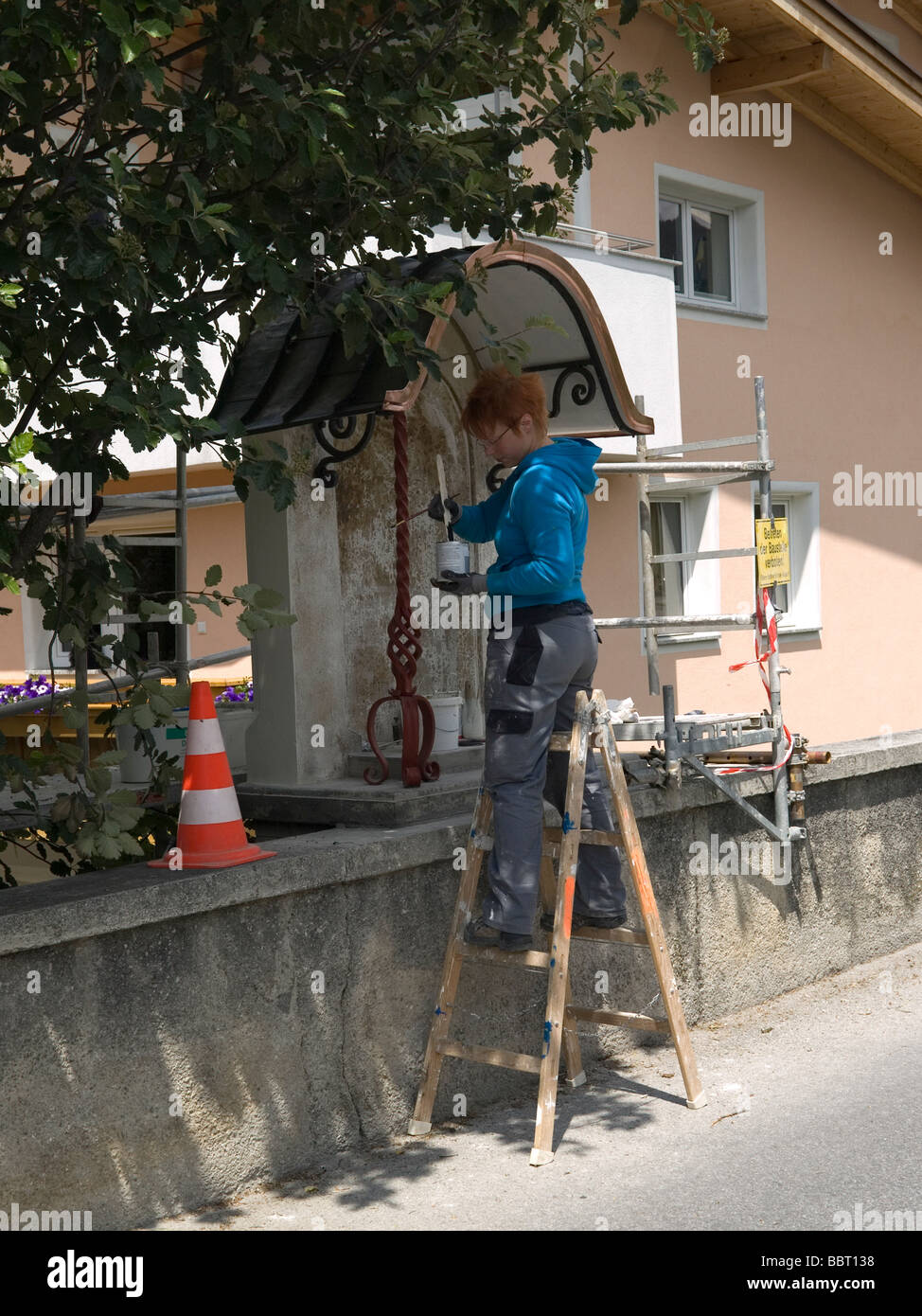 Young woman artist painter renovating a roadside shrine in Fulpmes Austria Stock Photo