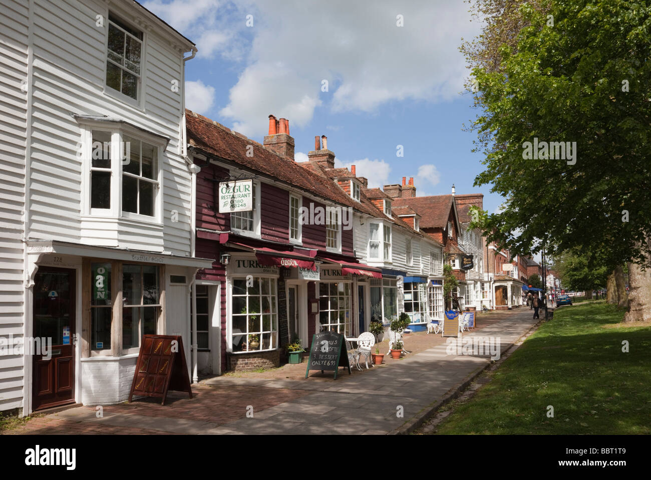 Small shops in 15th to 18th century buildings on tree-lined High Street in old Cinque Port Wealden town. Tenterden Kent England UK Britain Stock Photo