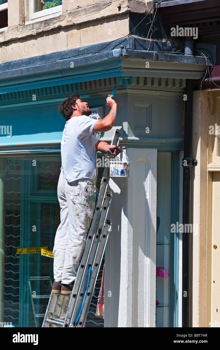 Painter and decorator painting outside of shop front Stock Photo