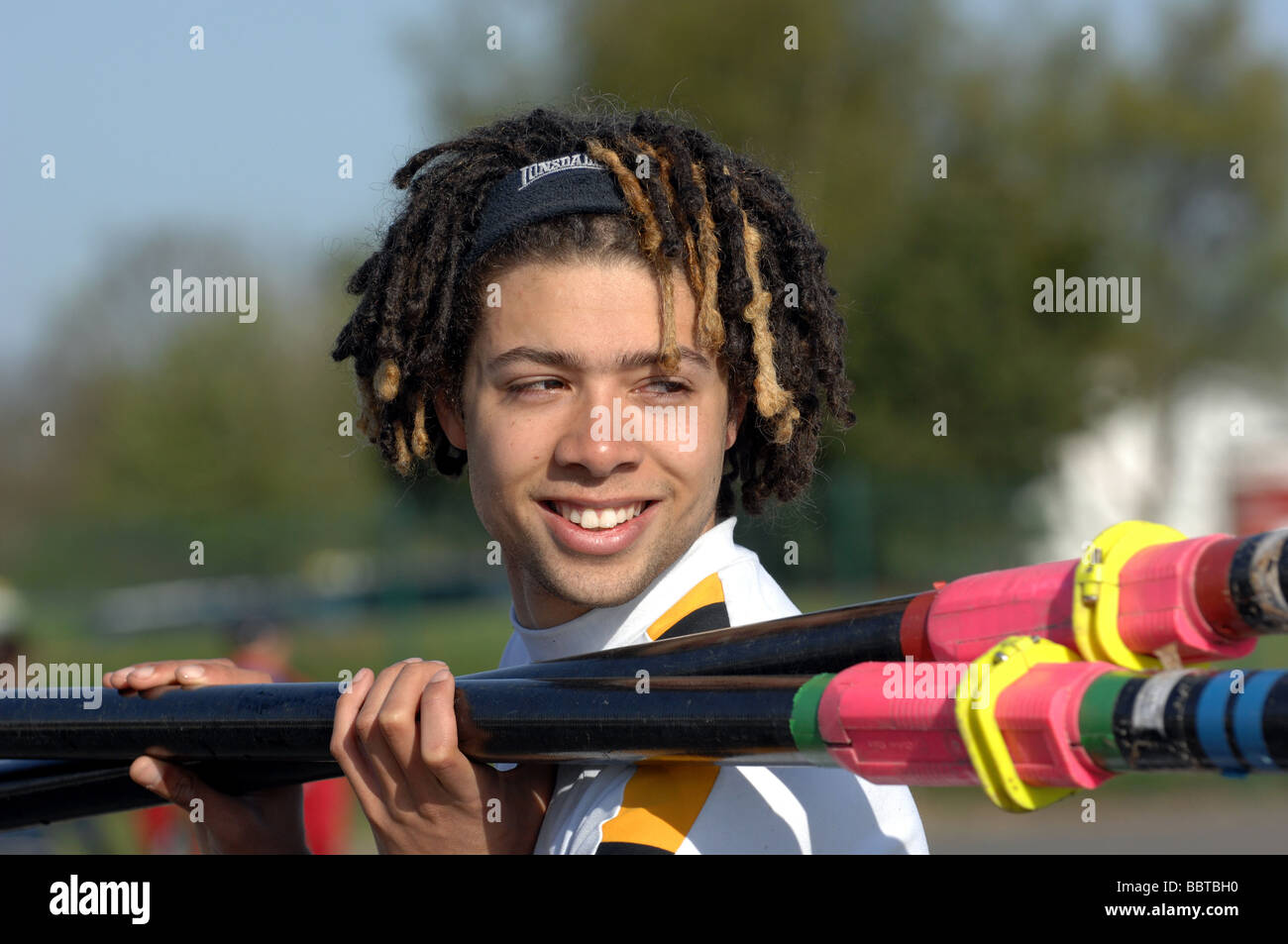 Happy smiling dreadlocked rower carrying oars Stock Photo