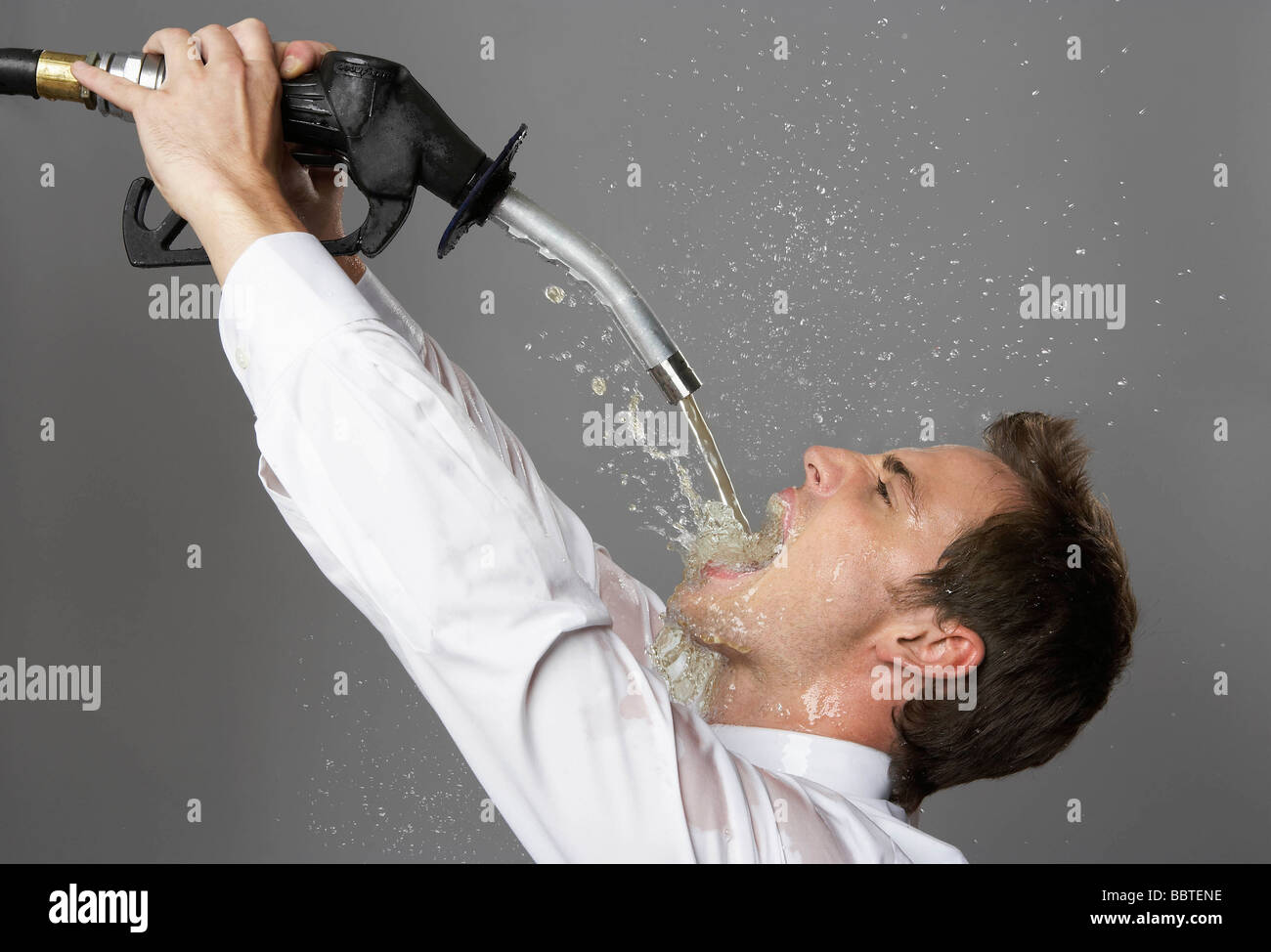 Business man drinking from petrol pump Stock Photo