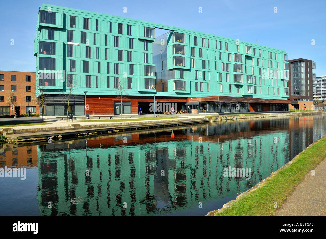 The Regents canal Mile End towpaths with waterside Queen Mary University of London green buildings alongside waterway East London England UK Stock Photo