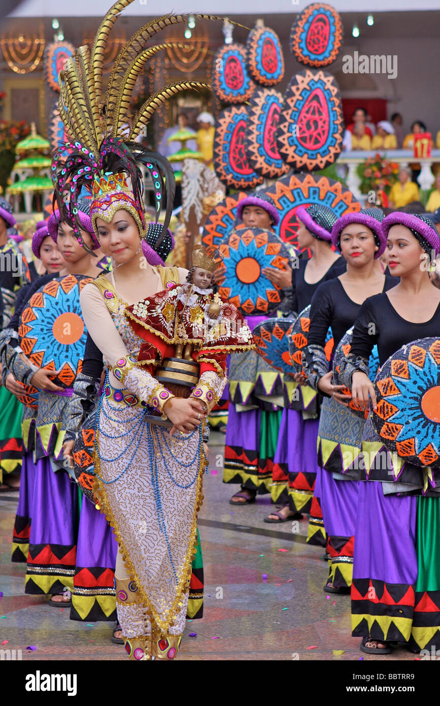 woman with sinulog costume and a Santo Niño doll in the sinulog parade