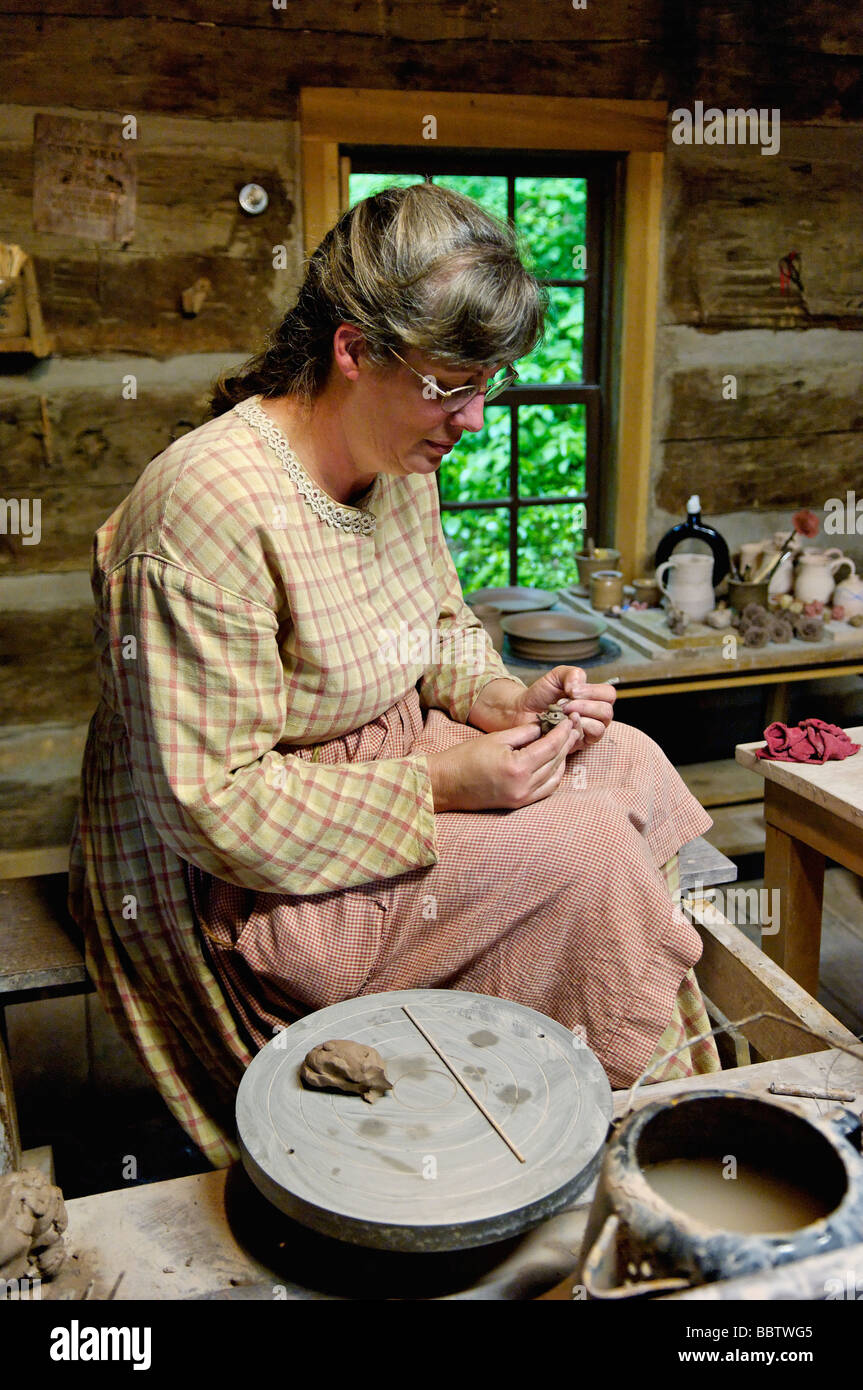 Woman In Pioneer Period Costume Working With Clay In Log Cabin At