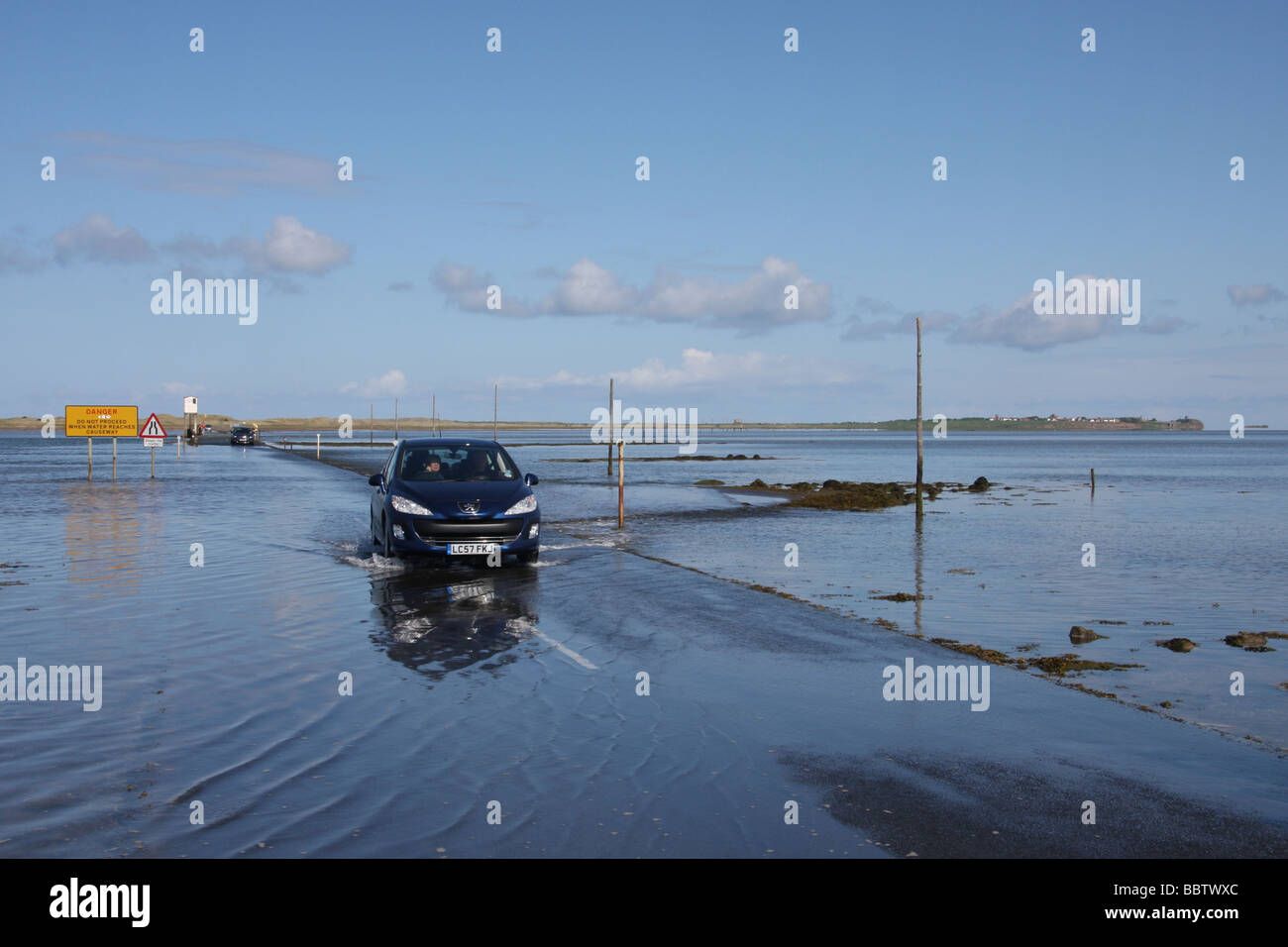 Car crossing causeway to Beal from Holy Island, as tide ebbs Stock Photo