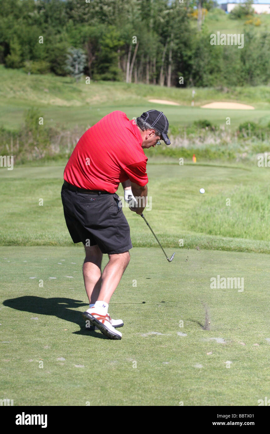 An adult male golfer hitting a golf shot with an iron from the tee box
