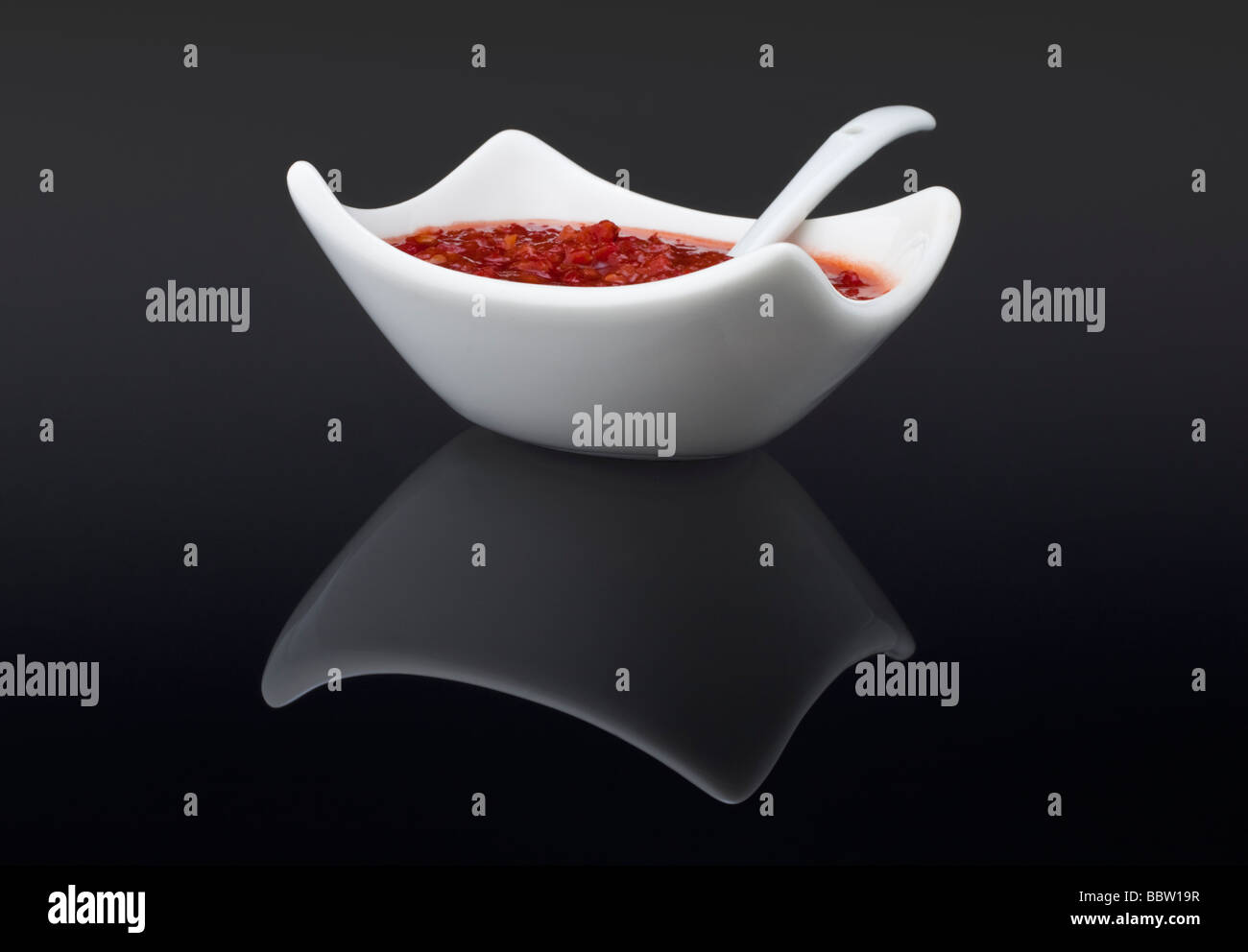 Chilli sauce in a white dish with serving spoon Stock Photo