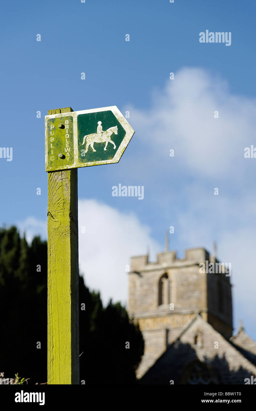 Public bridleway sign with village church in rural Dorset South west England UK Stock Photo