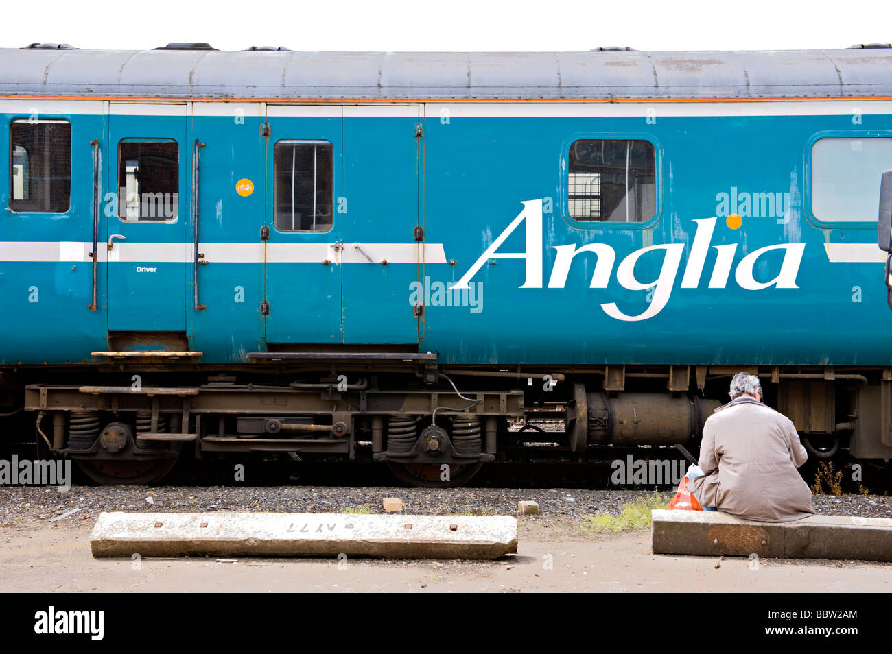 A man takes a break in front of a scrapped Anglia trains railway coach at The Easleigh Railway Depot open day. Stock Photo