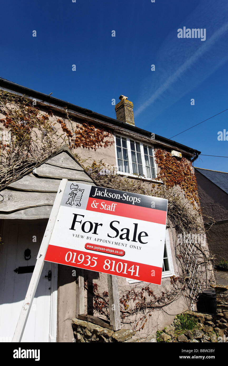Old rural village cottage with estate agents for sale sign Dorset South West England UK Stock Photo