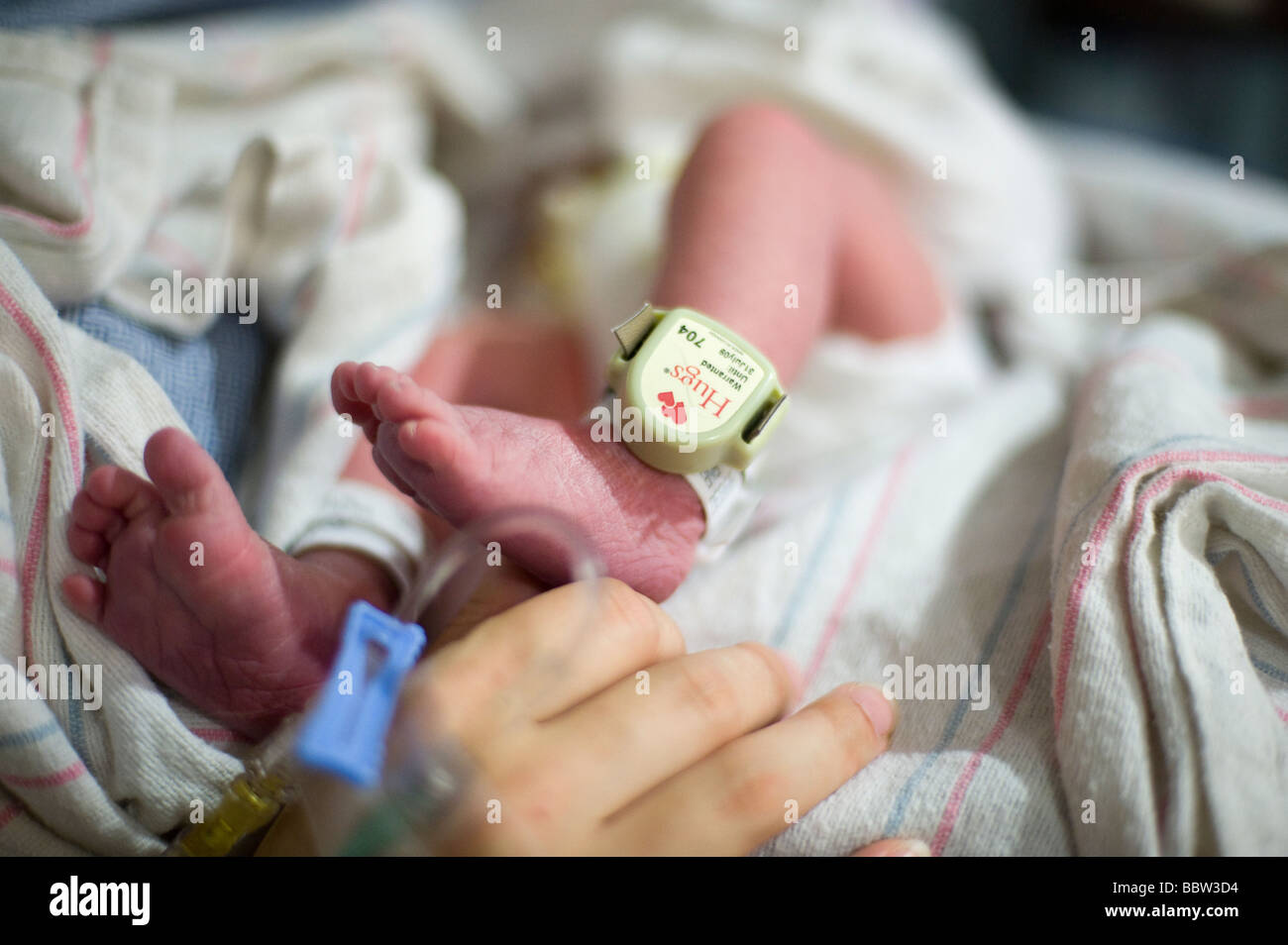 Newborn boy's leg fitted with "baby lojak", a sensor which will sound if the baby leaves a secure area Stock Photo