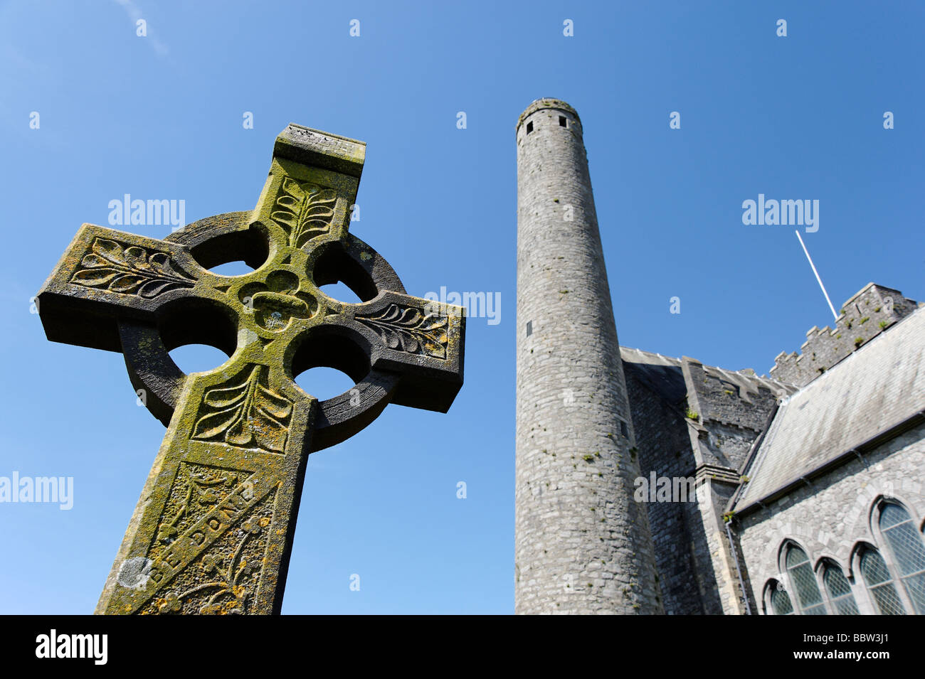Celtic cross in front of Saint Canices cathedral and tower in Kilkenny city Southern Ireland Stock Photo