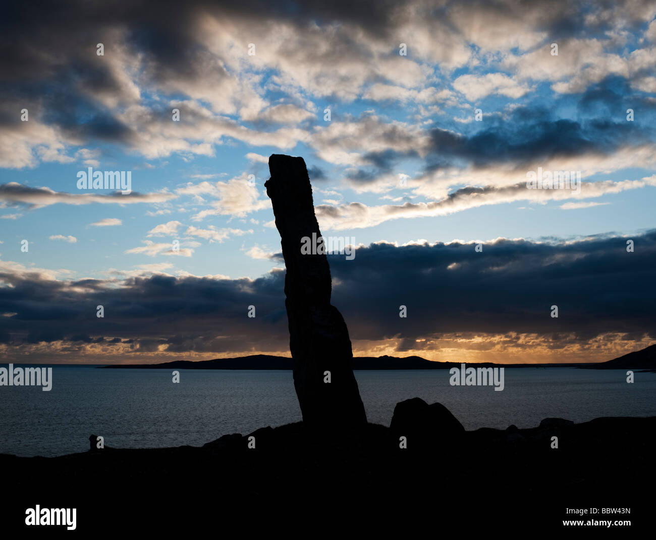 Mcleods standing stone sunset silhouette, looking over sound of Taransay, Isle of Harris, Outer Hebrides, Scotland Stock Photo