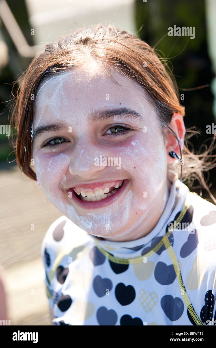 A happy smiling young pre teen girl with high factor sun block white cream on her face to protect her from sunburn, UK Stock Photo