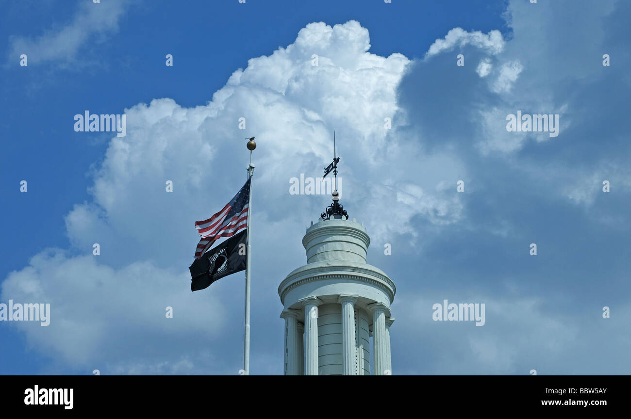 architectural detail of a cupola on top of a roof on a government building, white with puffy clouds in sky and flags on pole Stock Photo