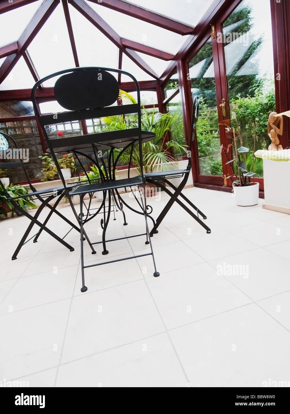 conservatory tables chairs plants room in house next to garden Stock