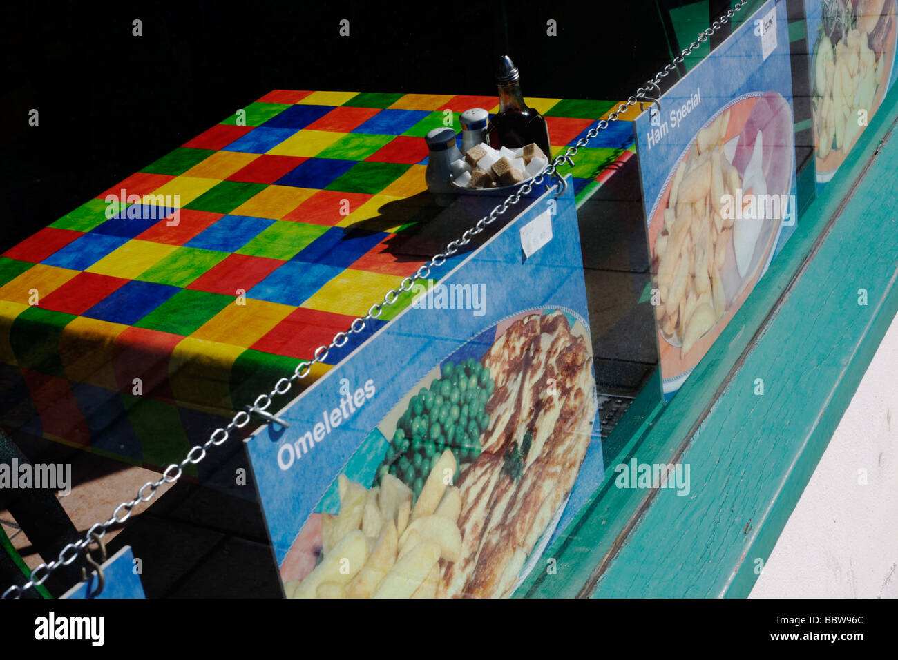 Brightly-coloured chequered table cloth and menu   in a seaside cafe window in Weston-super-Mare Stock Photo