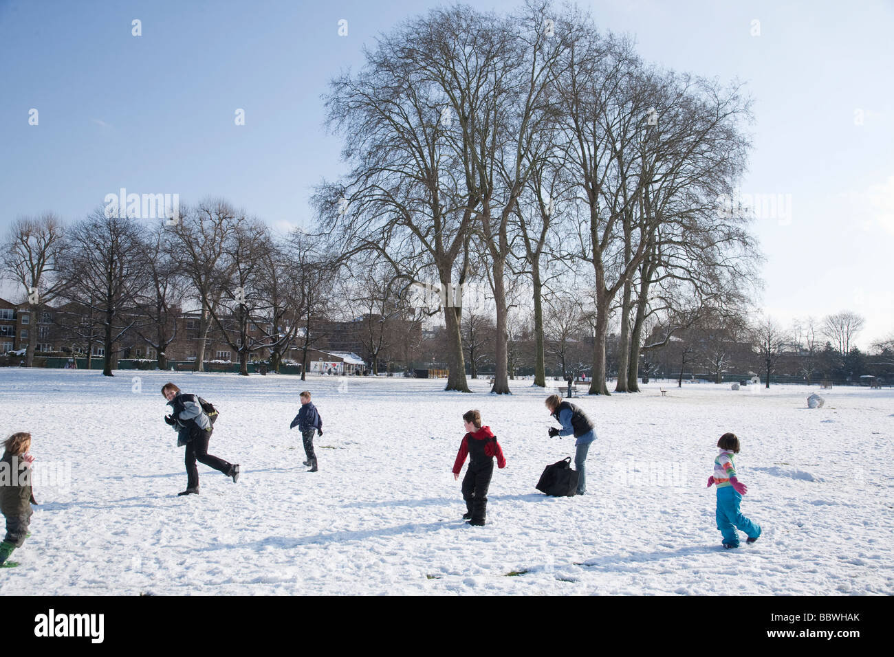People playing in snow covered Ravenscourt Park in London on a clear sunny day in winter Stock Photo