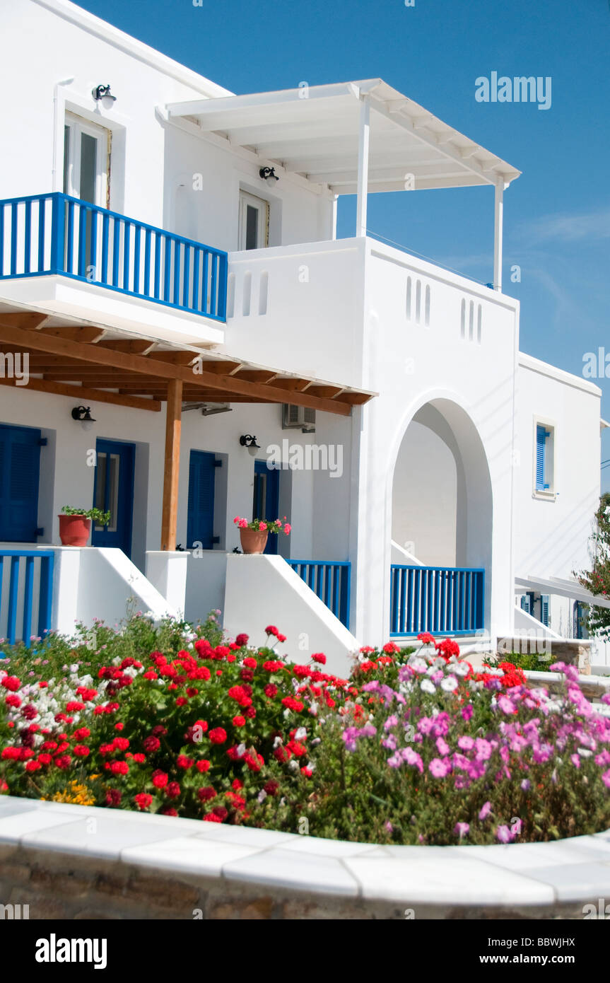 whitewashed architecture with arches and blue shutters and rails common to the greek cyclades island with flowers Stock Photo