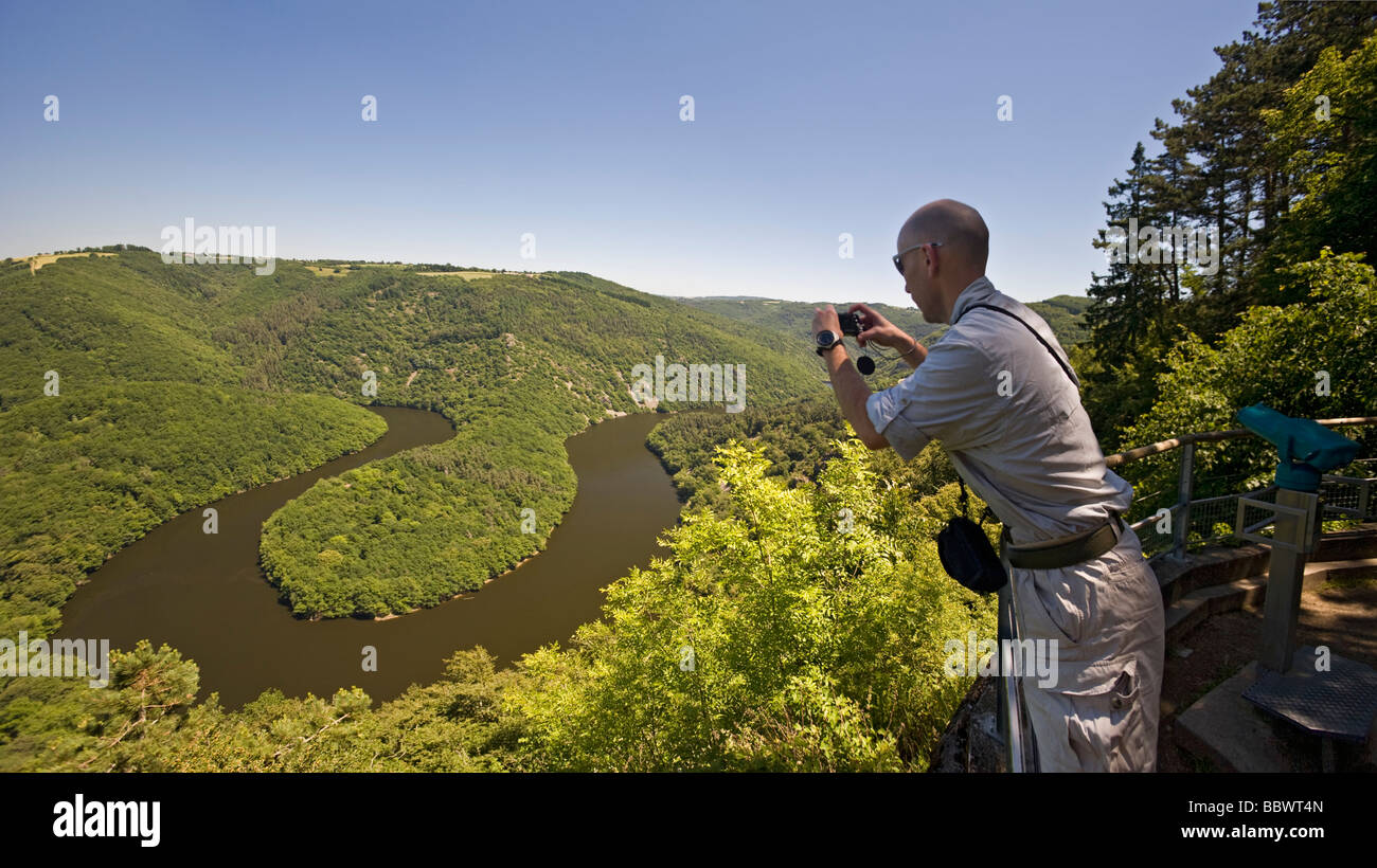 A young man photographing the Queuille meander (Puy-de-Dôme - France). Homme photographiant le méandre de Queuille sur la Sioule Stock Photo
