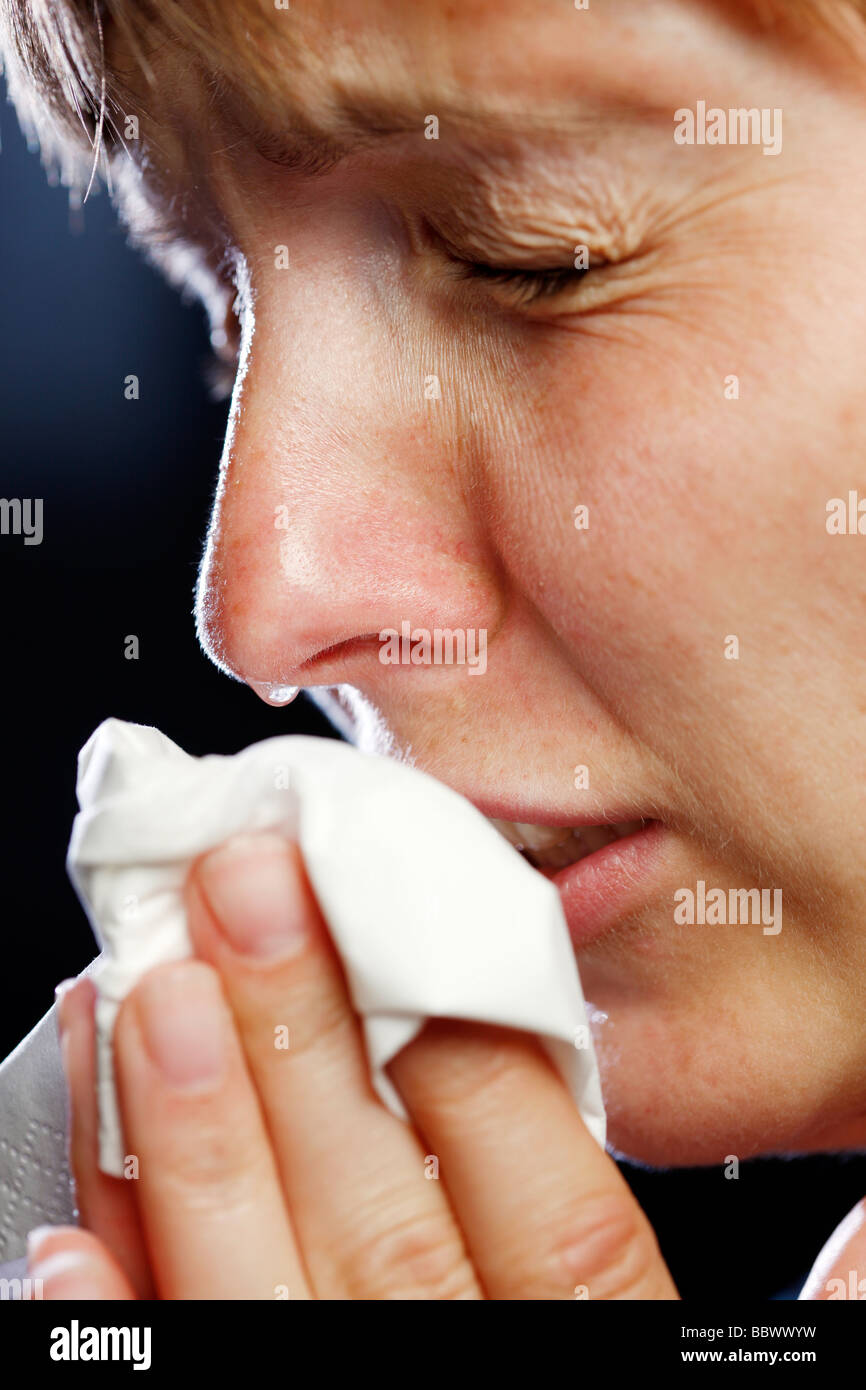 Woman is sneezing sniveling, has a cold or an allergy, uses a soft