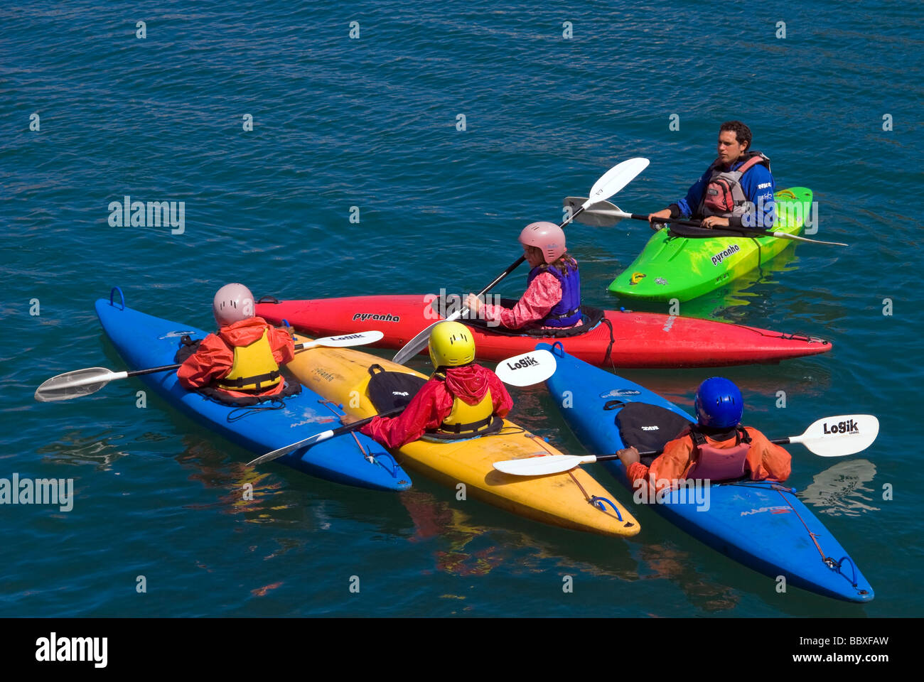 Colourful sea kayaks. Canoeing at sea. Sea canoes UK. Four children & one instructor in Pyranha canoe. Stock Photo