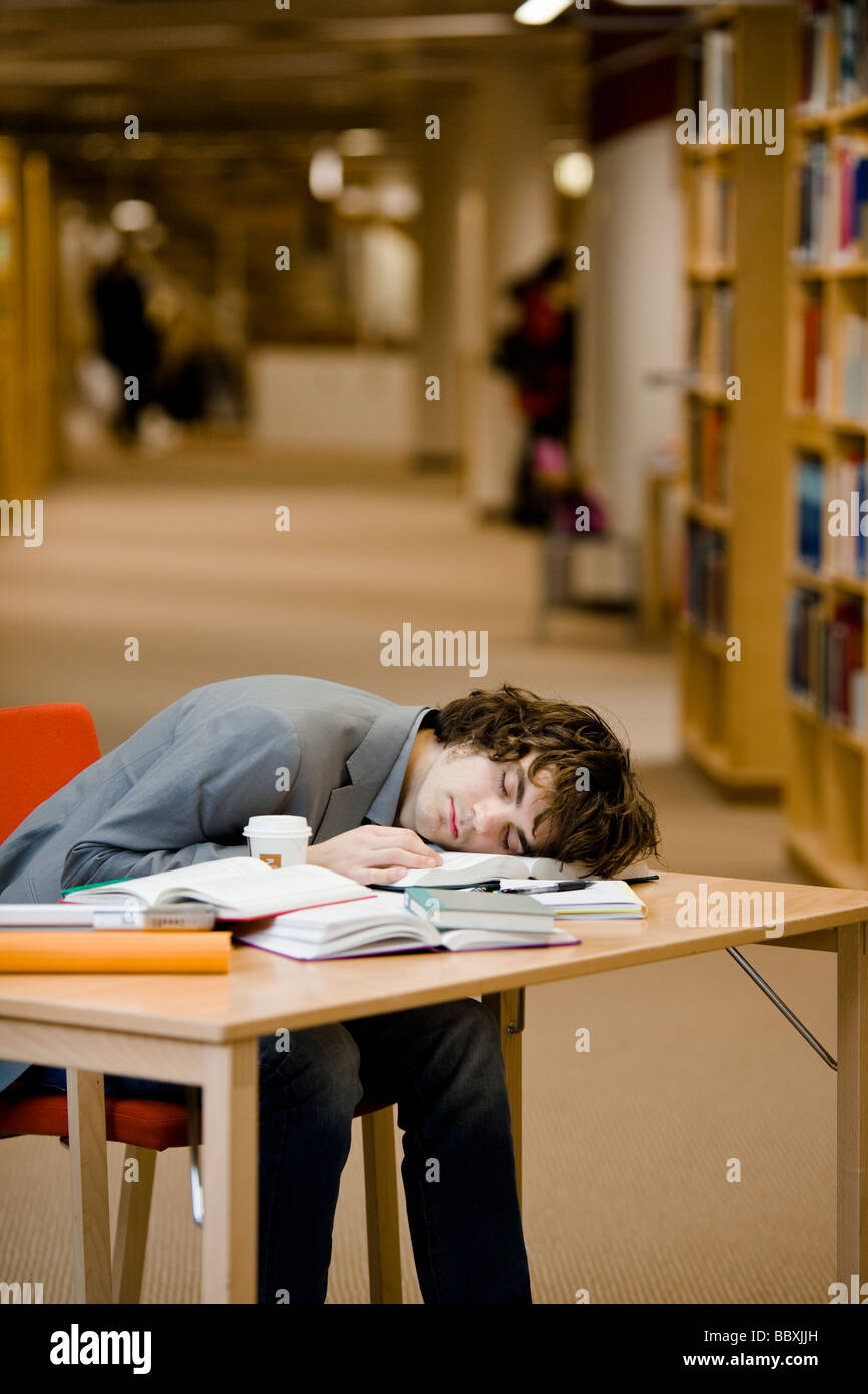 A student who has fallen asleep in a library Sweden. Stock Photo