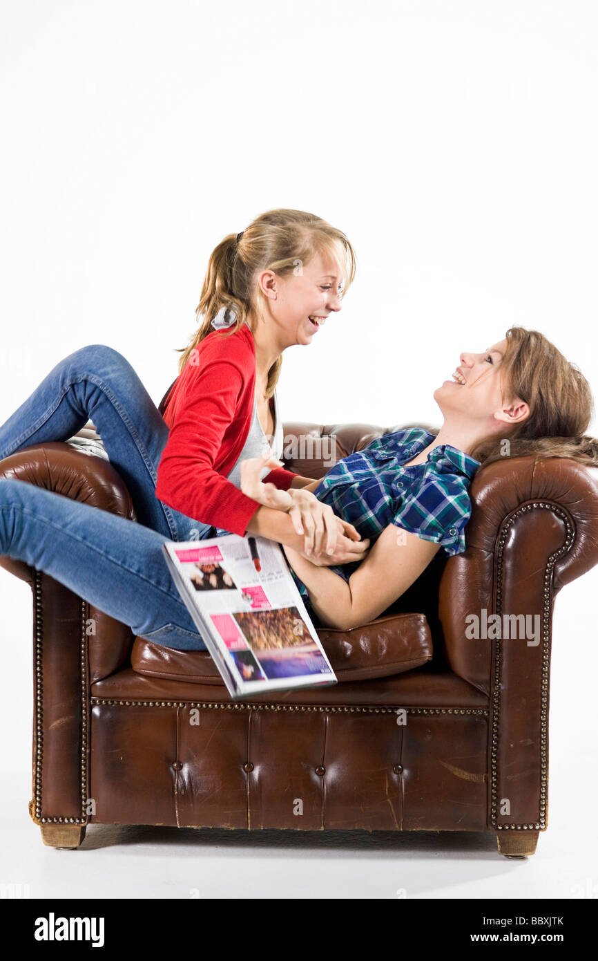 Teenage girls relaxing in an armchair. Stock Photo