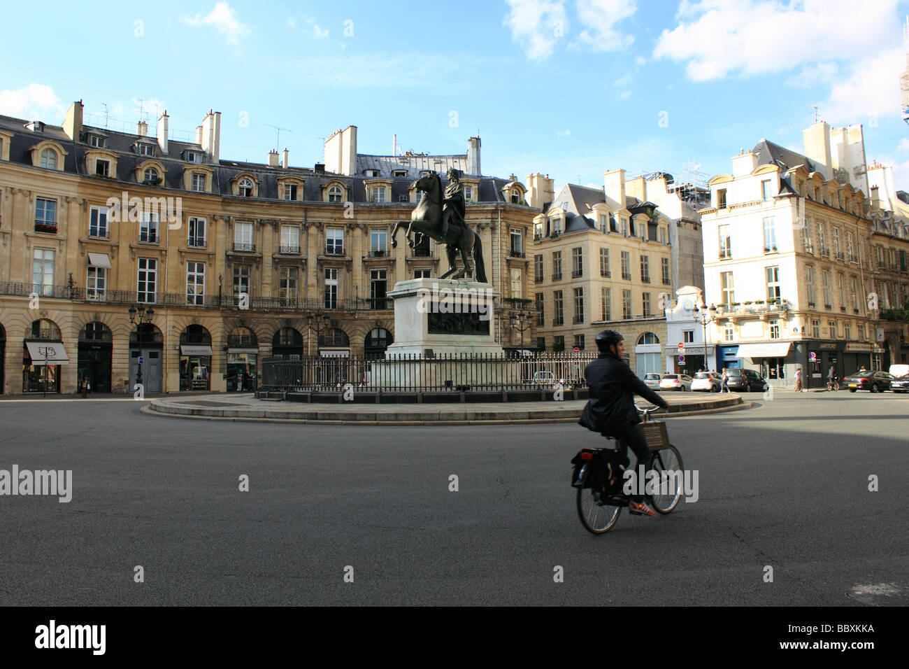 Cyclist enjoying freedom of Paris passing through Place des Victoires, Paris in front of equestrian statue of Louis XIV Stock Photo