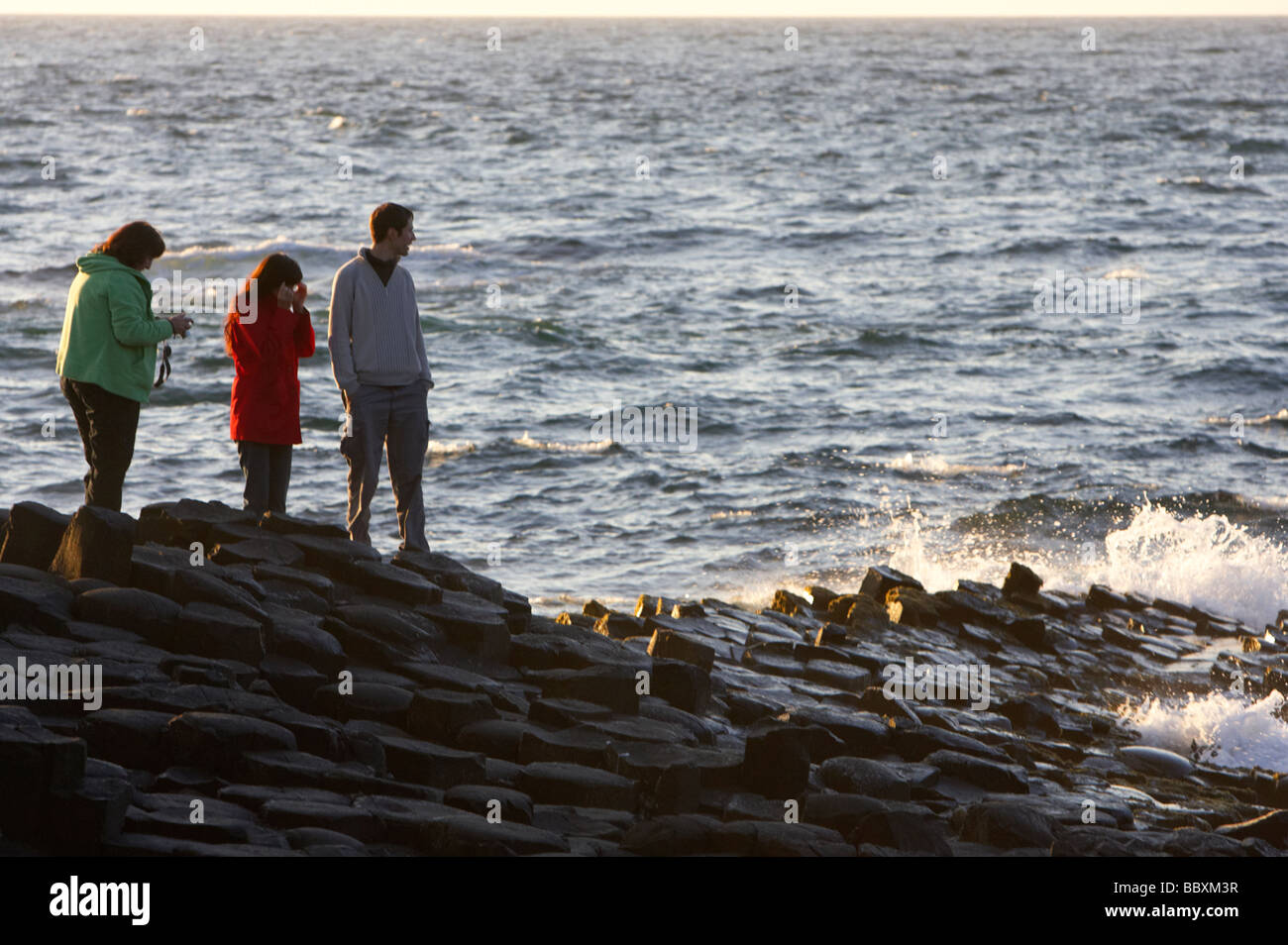 tourists watch the waves on the giants causeway county antrim coast northern ireland uk europe Stock Photo