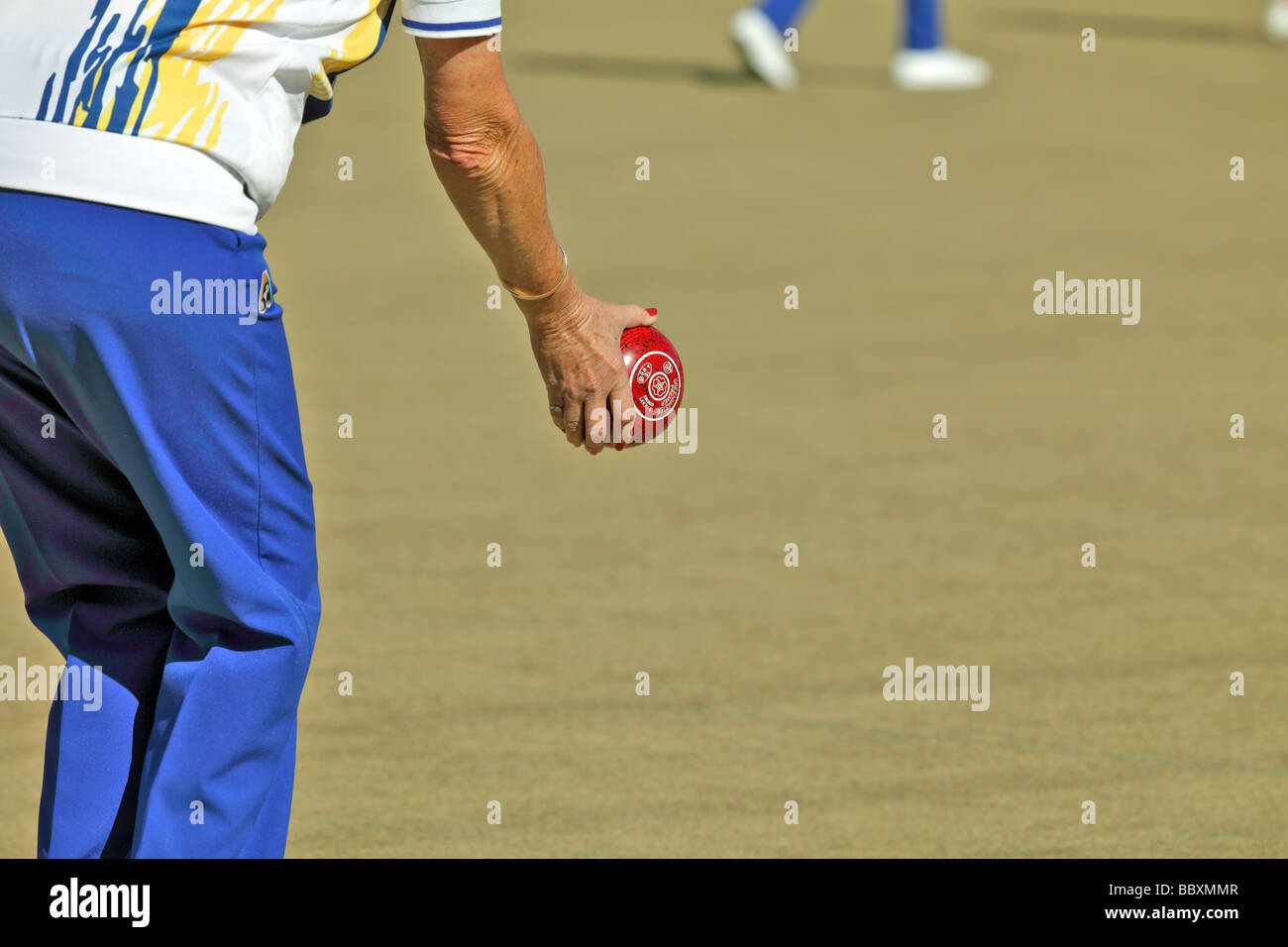 Woman at a lawn bowls tournament showing technique and bowling equipment Stock Photo