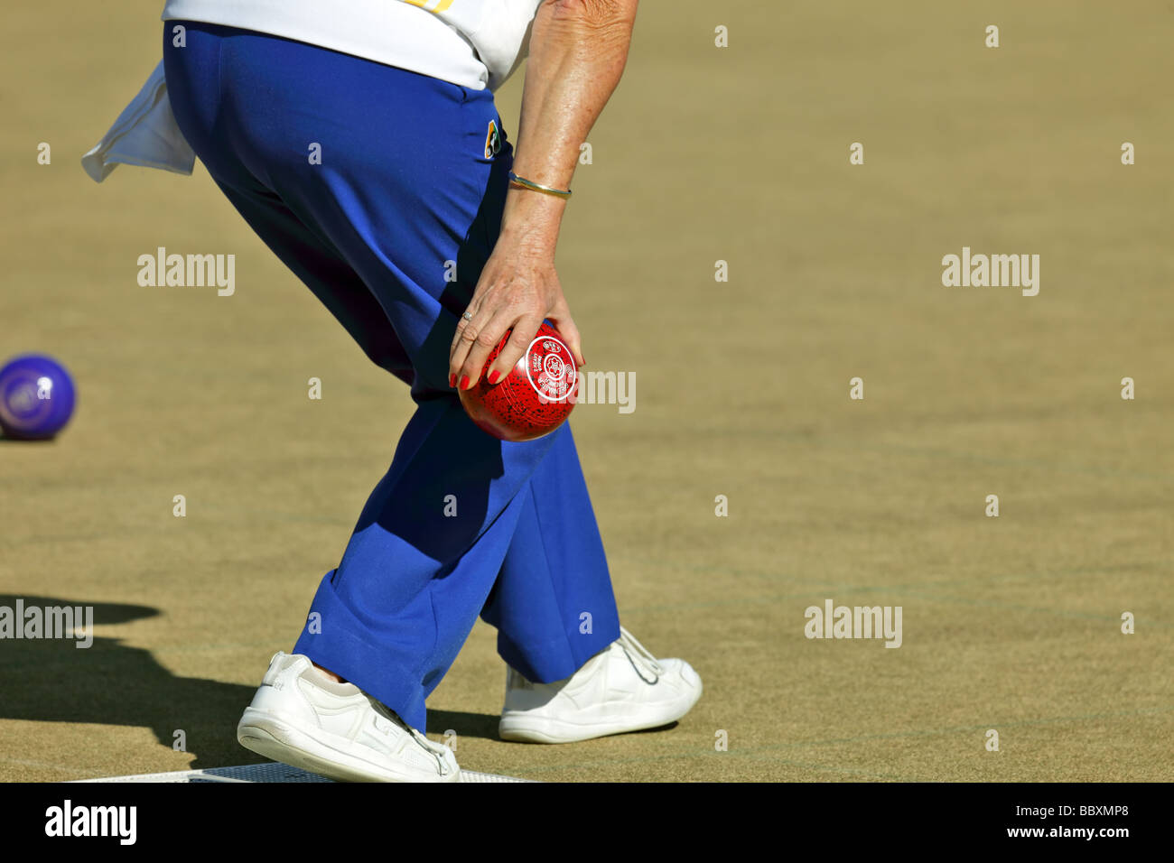 Woman at a lawn bowls tournament showing technique and bowling