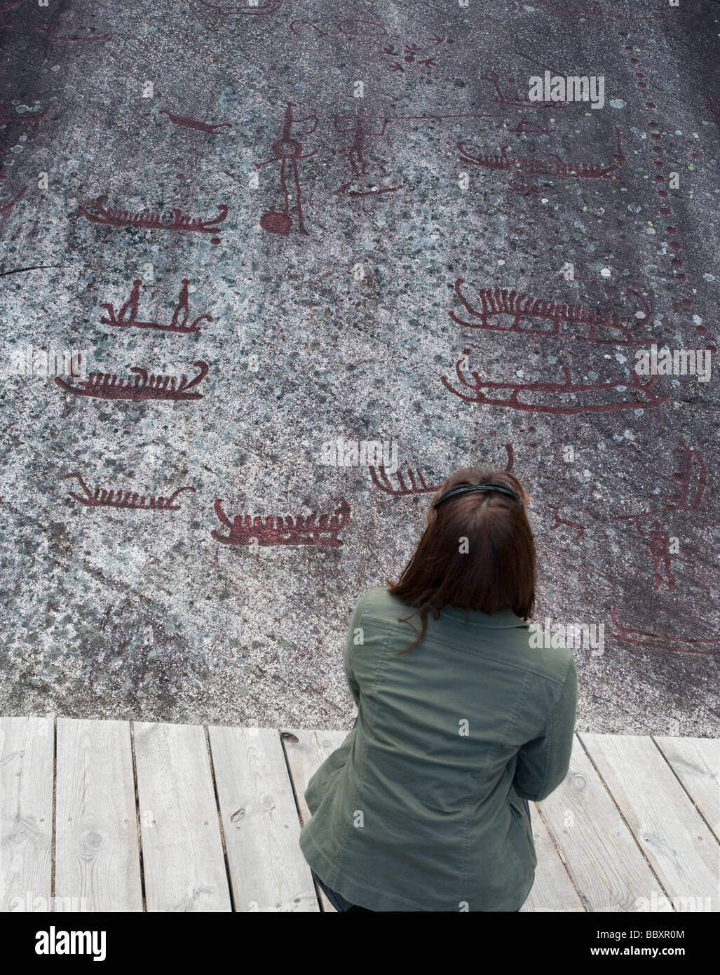 Woman looking at ancient Bronze Age rock carvings at Vitlycke on Tanum plane in Sweden Stock Photo