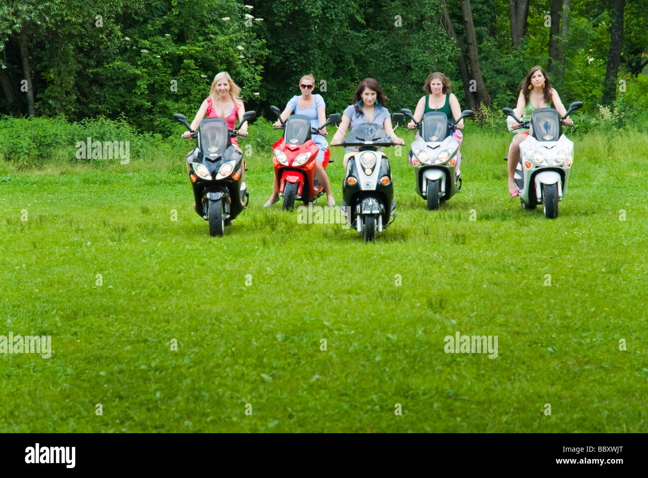Five girls on electric motorbikes driving in a park Stock Photo