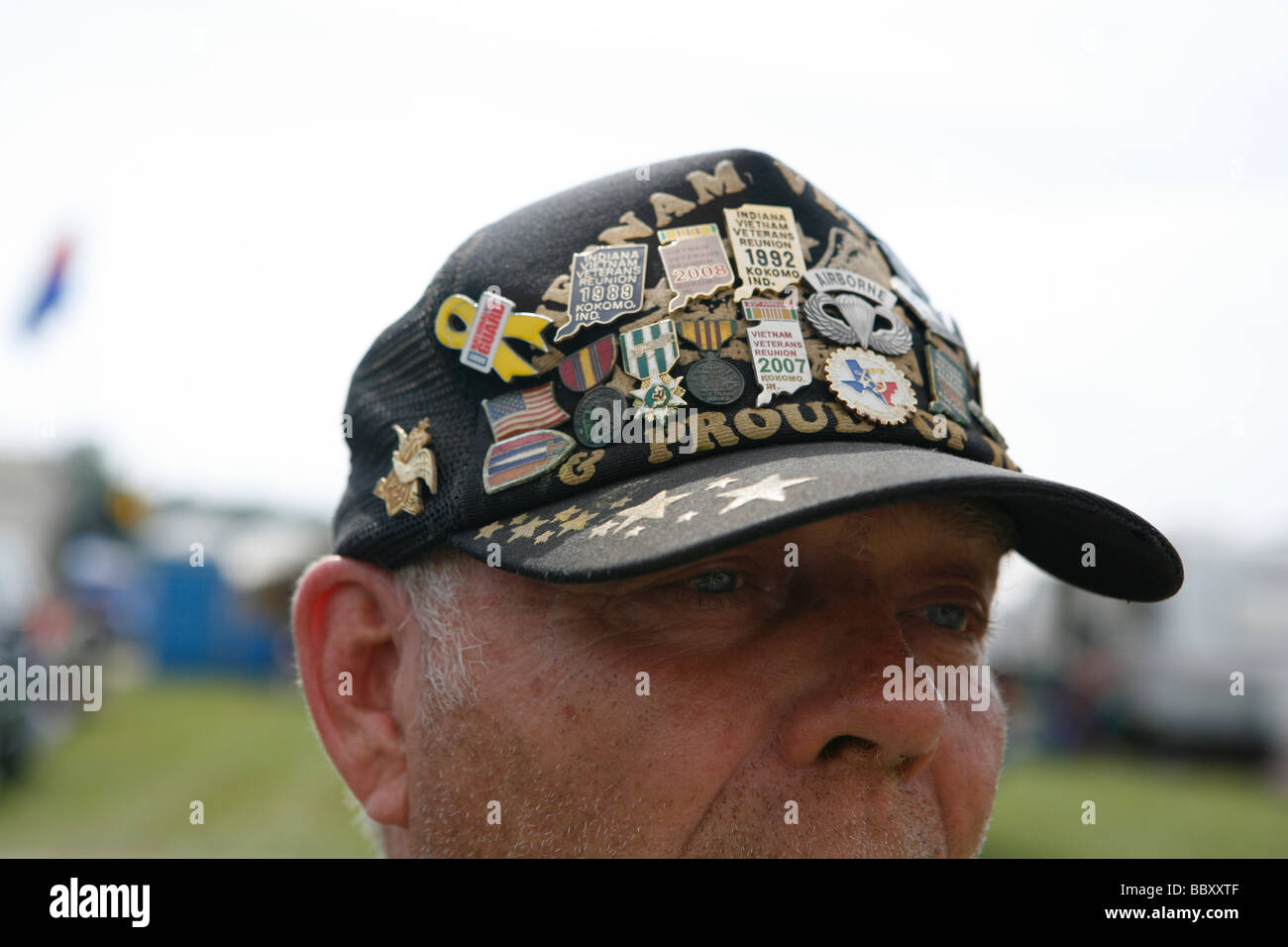 A Vietnam Veteran wears a hat covered with pins from previous reunions