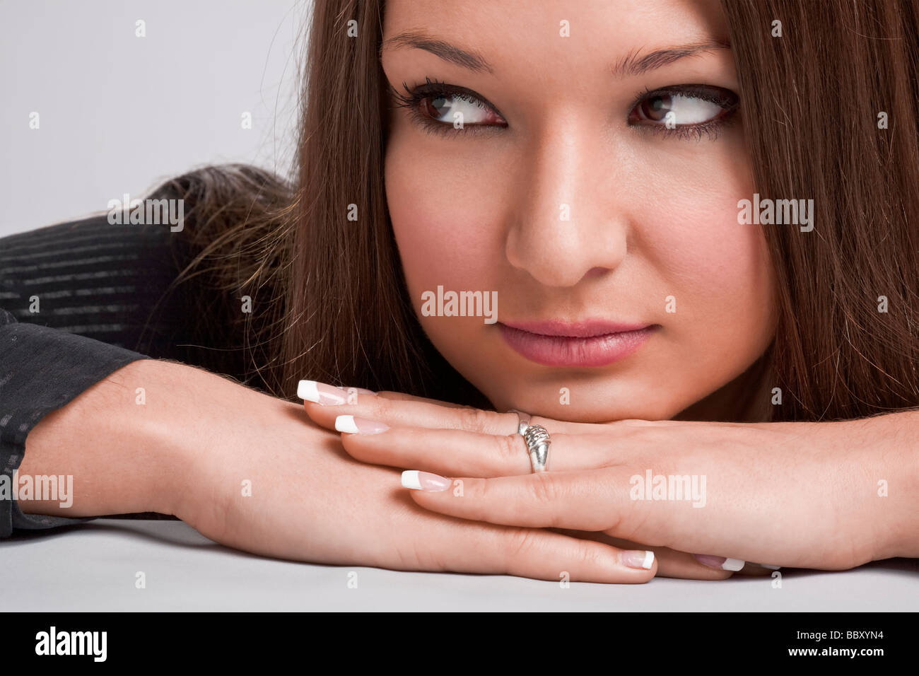 Young woman resting chin on hands and looking sideways Stock Photo Alamy