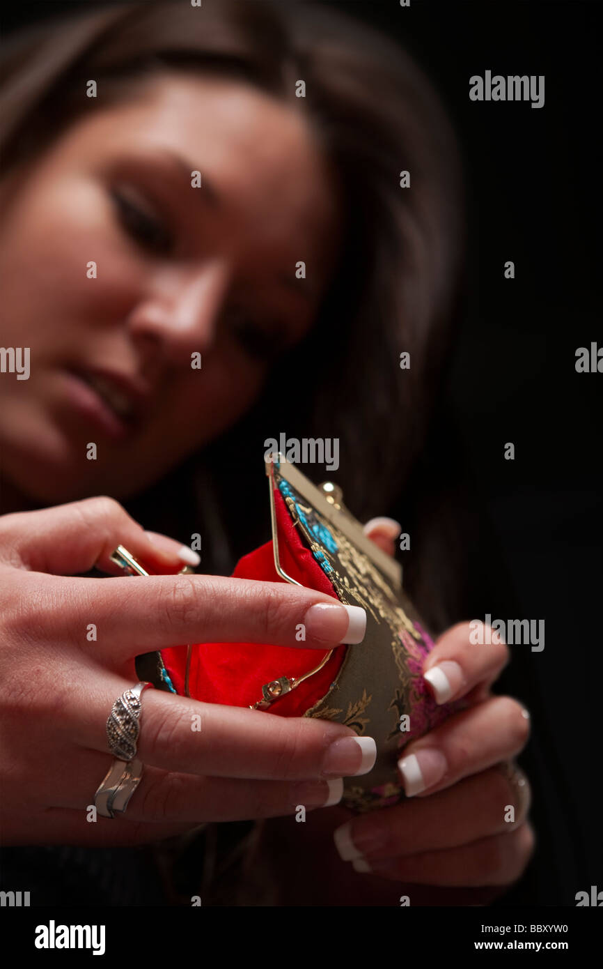 Worried woman looking into empty purse focus on purse Stock Photo