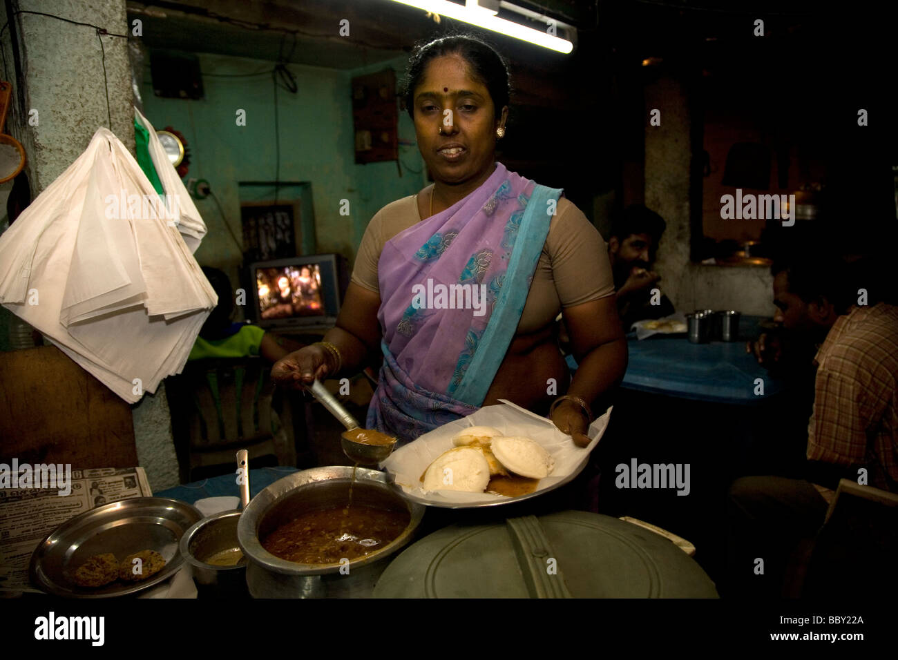 A roadside restaurant close to Chennai, India. The simple restaurant serves good, basic food. The woman serves idly. Stock Photo