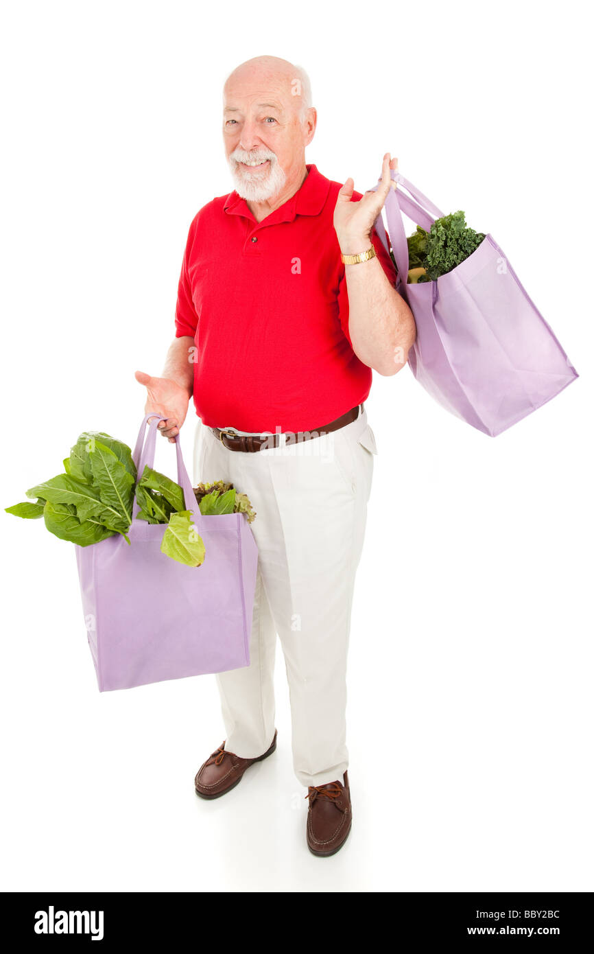 Handsome senior man shops for organic produce using reusable cloth grocery bags Isolated on white  Stock Photo