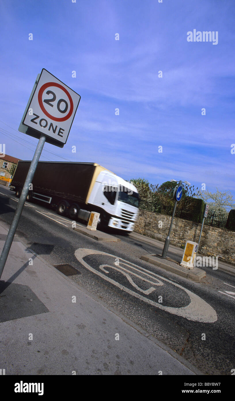 lorry passing 20 miles per hour speed limit zone warning sign on road through village near leeds yorkshire uk Stock Photo