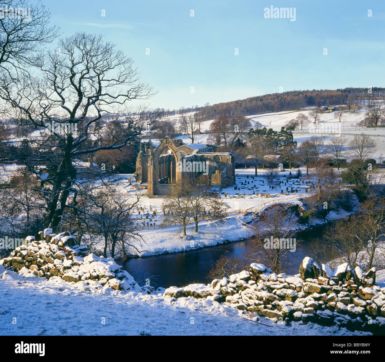 River Wharfe flowing by Bolton Priory surrounded by winter snow by Bolton Abbey Yorkshire Dales UK Stock Photo