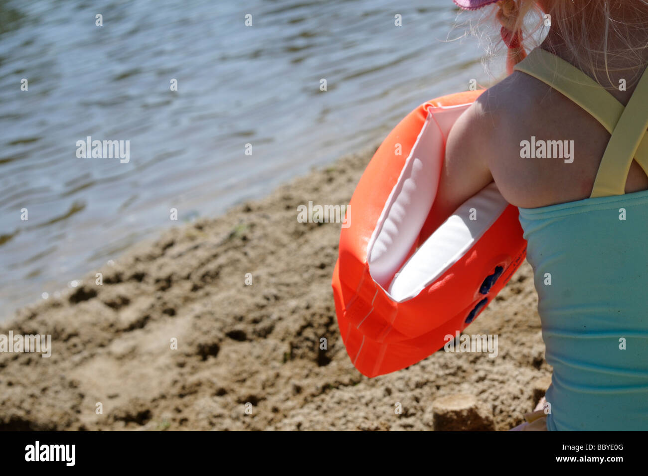 Stock photo of a 3 year old girl wearing her armbands on the beach