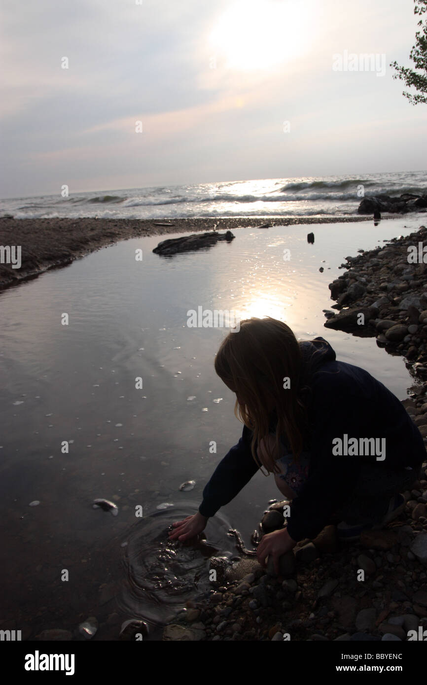 Girl playing with rocks by stream Stock Photo