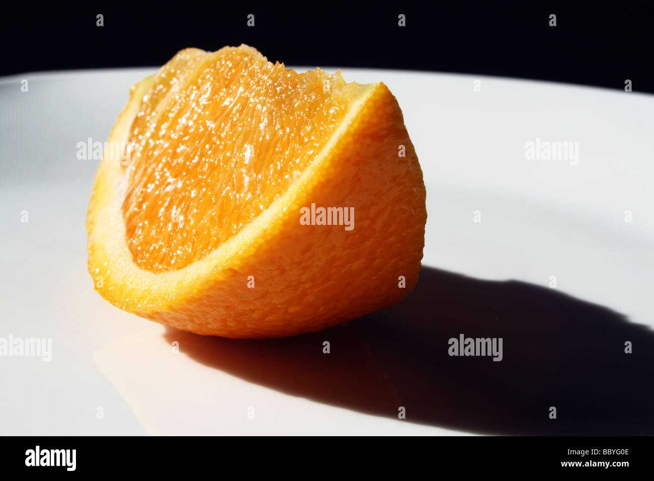 Orange Slice on a White Plate in Sunshine Stock Photo