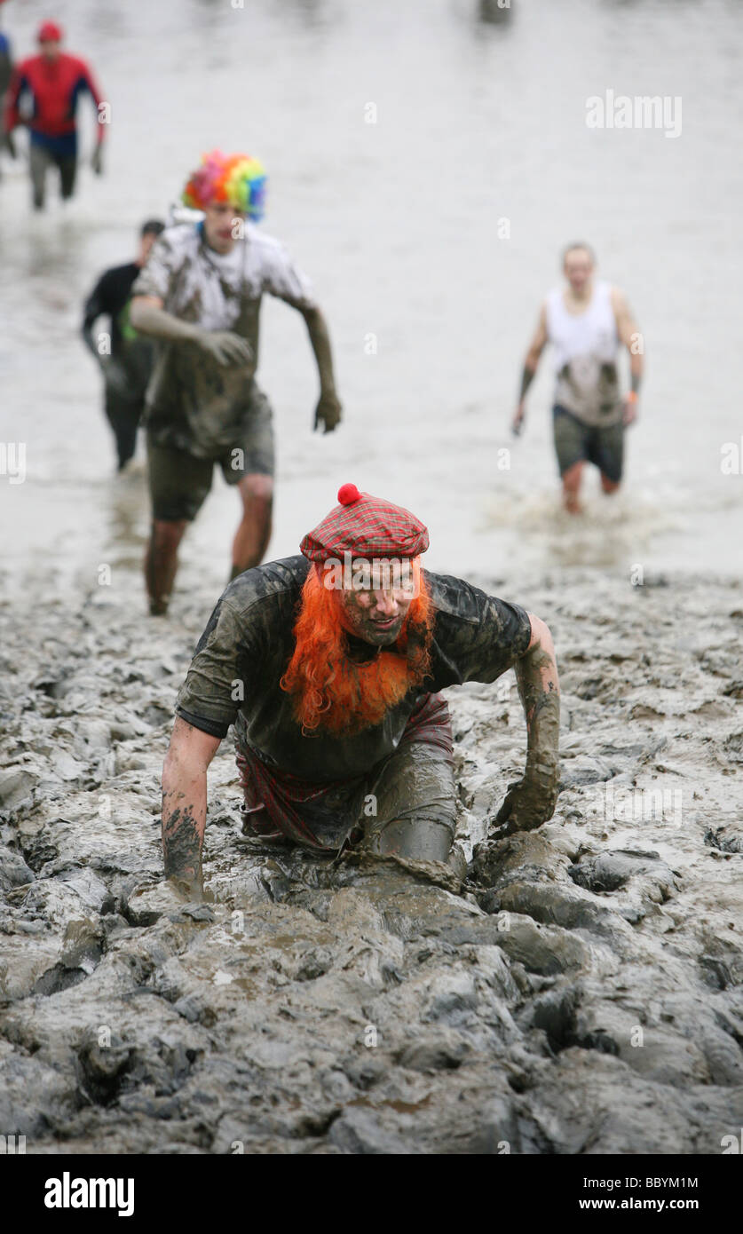 A contestant in fancy dress crawls towards the finish of the Mad Maldon Mud Race held in the river Blackwater at Maldon Essex Stock Photo
