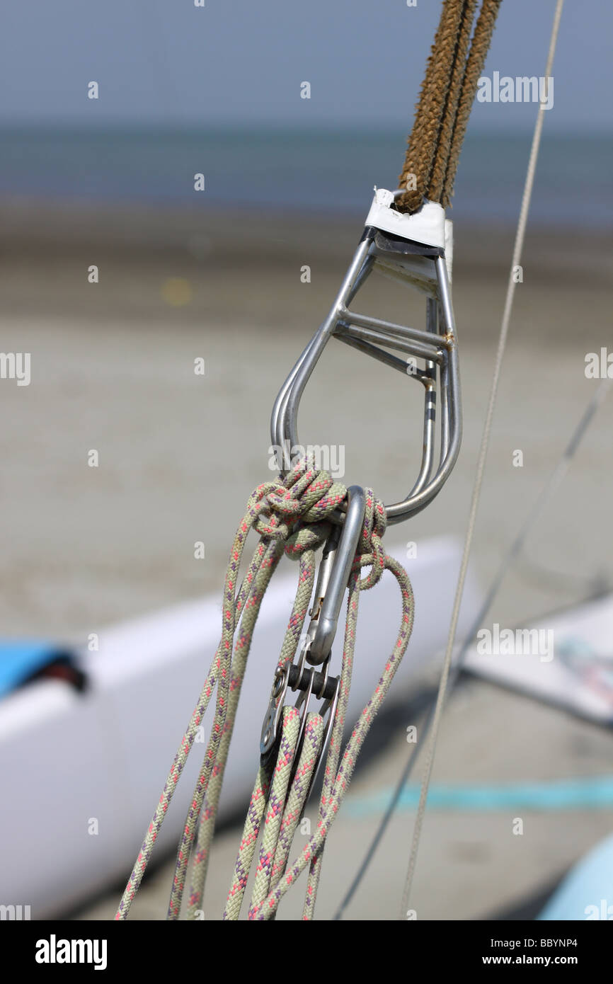 Trapeze ropes with pulley block from a sail boat on a beach Stock Photo
